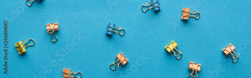 panoramic shot of colorful paper clips isolated on blue