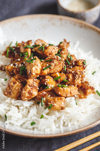 Sesame chicken pieces with white rice served spring green onions. Chinese traditional dish.