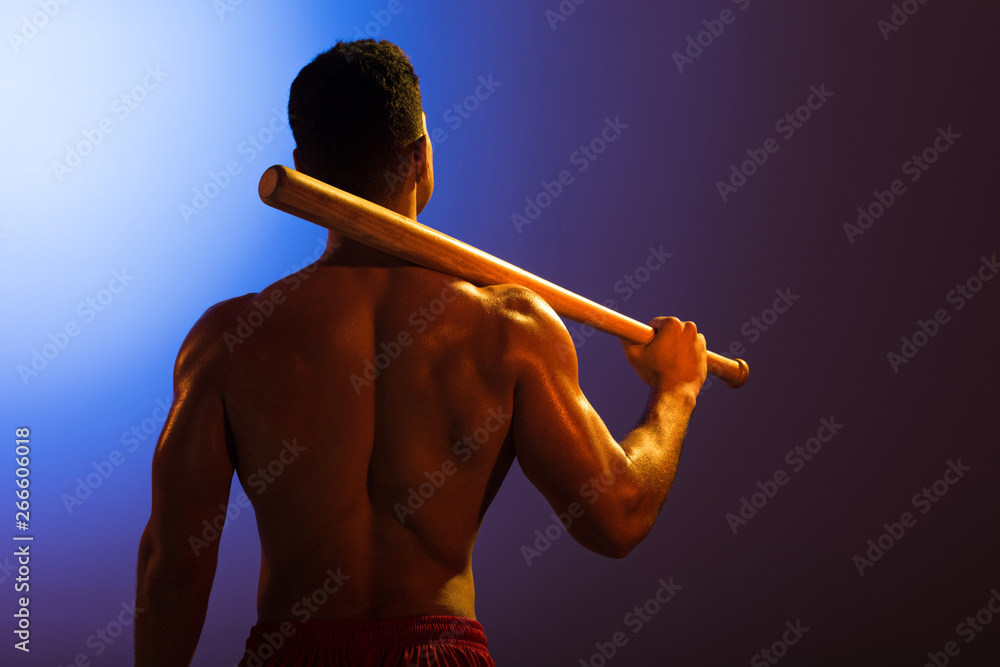 Φωτογραφία back view of athletic mixed race man with baseball bat on blue and dark purple g