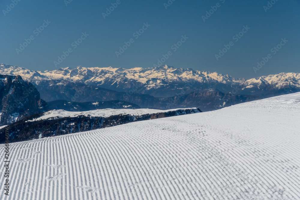 Panorama of Dolomites Alps, Val Gardena, Italy with groomed piste in the foreground
