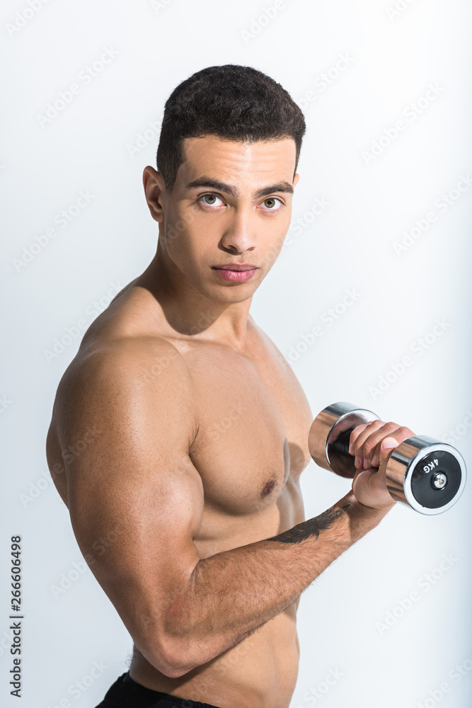 good-looking athletic mixed race man training with dumbbells and looking at camera on white