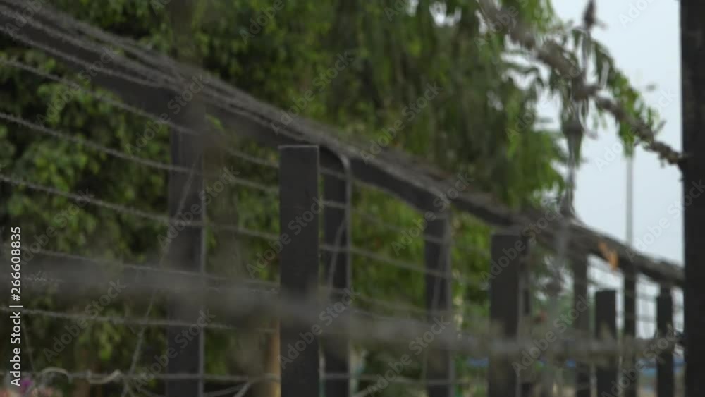 Rack focus to a close up of layers of barb wire along a high fence in the border between India and Pakistan Rack focus to a close up of layers of barb wire along a high fence in the border between India and Pakistan