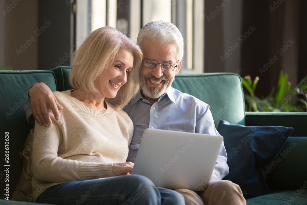 Smiling mature couple, wife and husband using laptop together at home Smiling mature couple, wife and husband using laptop together at home