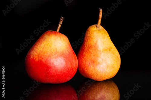 Group of two whole fresh red pear isolated on black glass