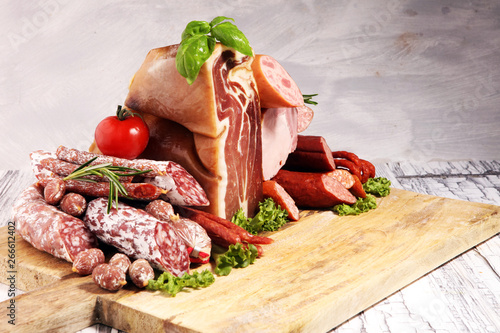 cold meat assortment with delicious salami and  fresh herbs . Variety of meat products including proscuitto, jamon  and sausages
