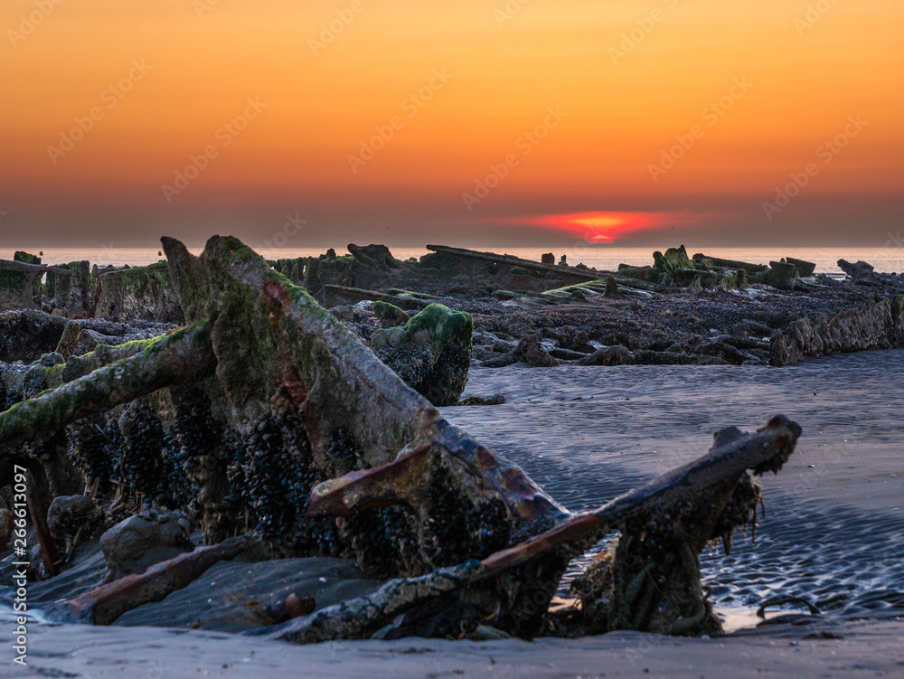 Close-up of an exposed shipwreck at low tide from World War II during sunset at the beach