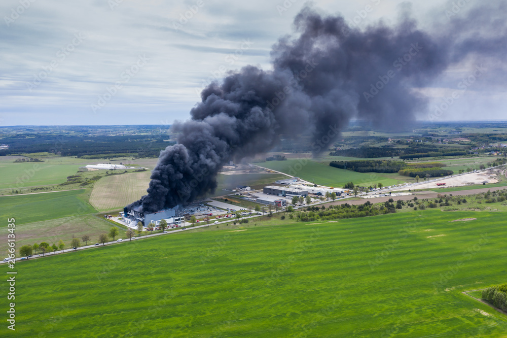 Aerial view of burnt industrial warehouse or logistics center building after big fire with huge smoke from burned roof