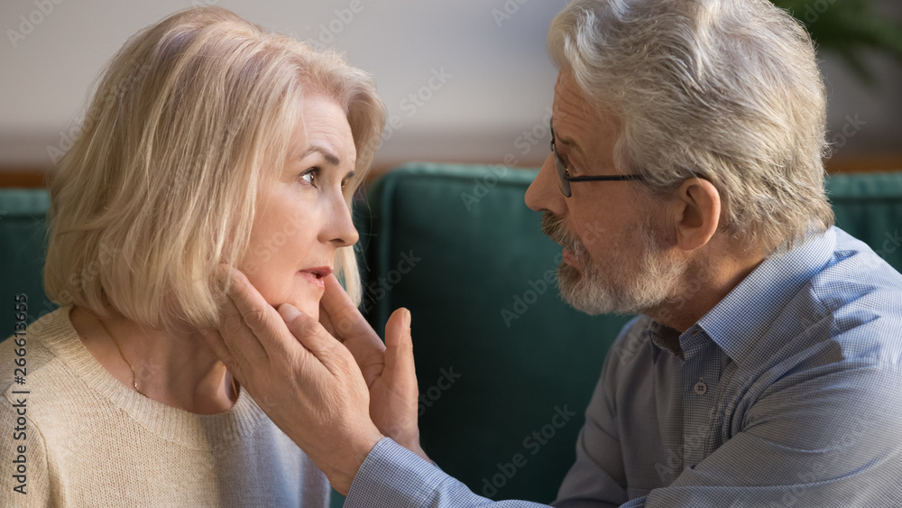 Middle aged husband stroking wife face, showing support and love Middle aged husband stroking wife face, showing support and love