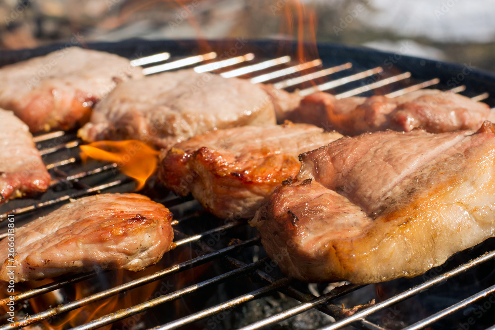 Meat steaks are fried on the barbecue grill.