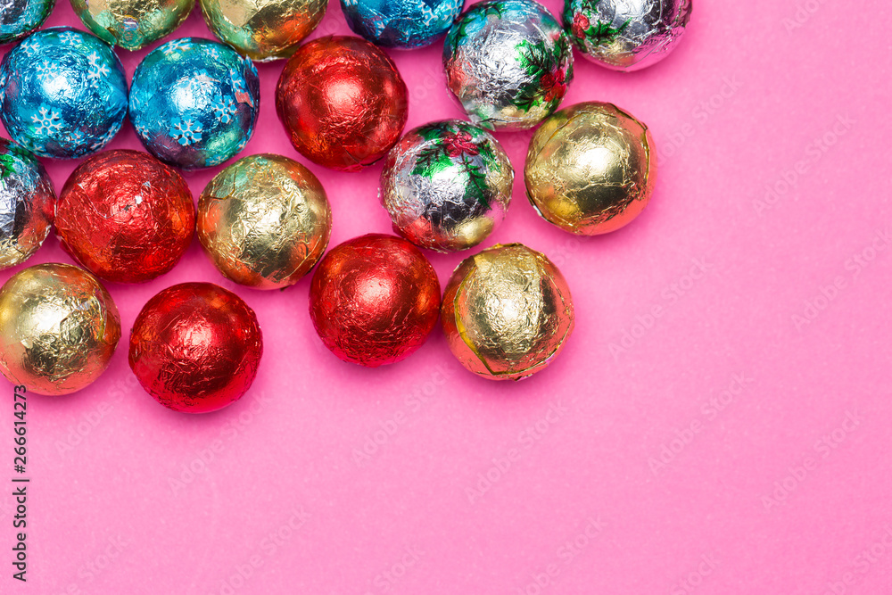 Chocolates in a multi-colored foil on a pink background Chocolates in a multi-colored foil on a pink background