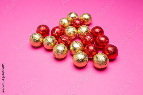 Chocolates in a multi-colored foil on a pink background