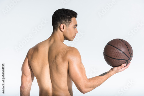 athletic mixed race man with  muscular torso holding brown ball on white © LIGHTFIELD STUDIOS