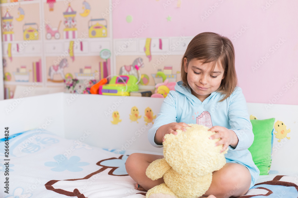 Cheerful little cute adorable baby girl playing with yellow teddy bear in her children room. Childhood, leisure kid time, happiness concept Cheerful little cute adorable baby girl playing with yellow teddy bear in her children room. Childhood, leisure kid time, happiness concept
