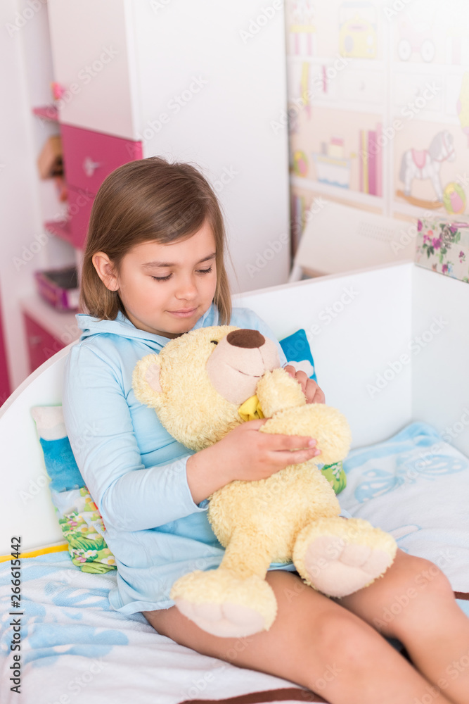Cheerful little cute adorable baby girl playing with yellow teddy bear in her children room. Childhood, leisure kid time, happiness concept Cheerful little cute adorable baby girl playing with yellow teddy bear in her children room. Childhood, leisure kid time, happiness concept
