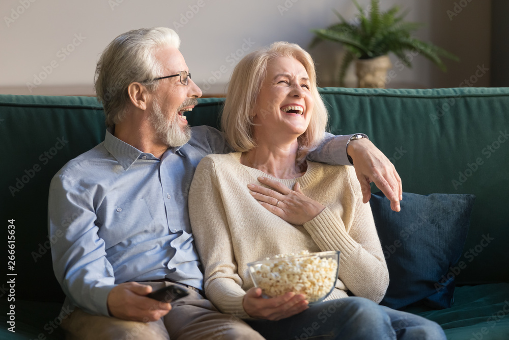 Laughing aged couple, man and woman watching tv and eating popcorn Laughing aged couple, man and woman watching tv and eating popcorn