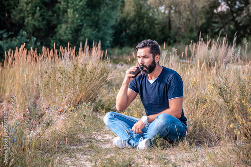 Stylish bearded vape man smokes e-cigarette exhales smoke on the ground. Electronic cigarette as alternative to tobacco. © Stop war in Ukraine!