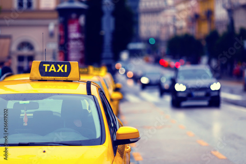 yellow taxi cars in row and blurred bald traffic in the background - european cityscape