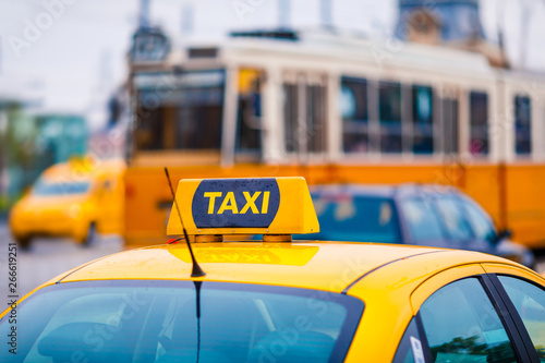 Yellow taxi cab with blurred tram and cars in the background