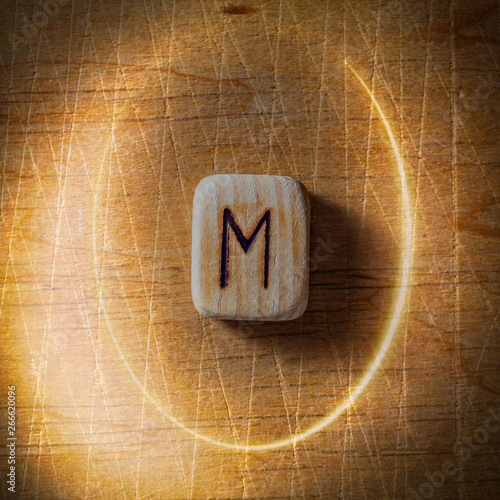 Ehwaz. Handmade scandinavian wooden runes on a wooden vintage background in a circle of light. Concept of fortune telling and prediction of the future. photo