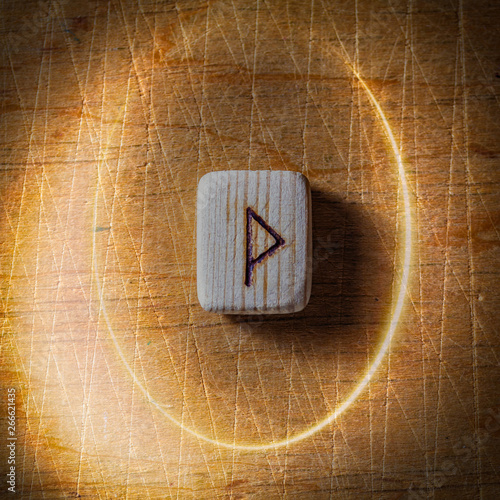 Wunjo. Handmade scandinavian wooden runes on a wooden vintage background in a circle of light. Concept of fortune telling and prediction of the future. photo