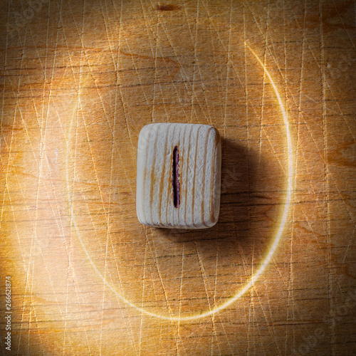 Isa. Handmade scandinavian wooden runes on a wooden vintage background in a circle of light. Concept of fortune telling and prediction of the future.