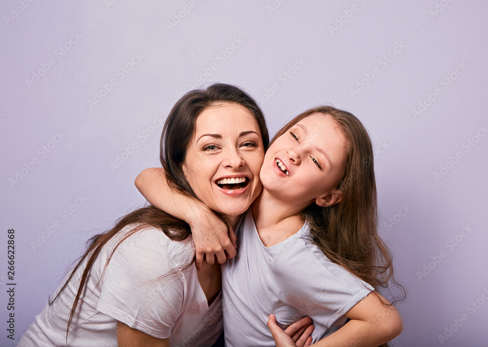 Happy mother and excited joying kid girl hugging with emotional smiling faces on purple background with empty copy space. Happy mother and excited joying kid girl hugging with emotional smiling faces on purple background with empty copy space.