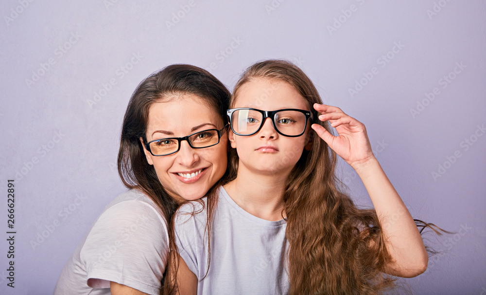 Happy young casual mother and smiling kid in fashion glasses hugging on purple background with empty copy space. Happy young casual mother and smiling kid in fashion glasses hugging on purple background with empty copy space.