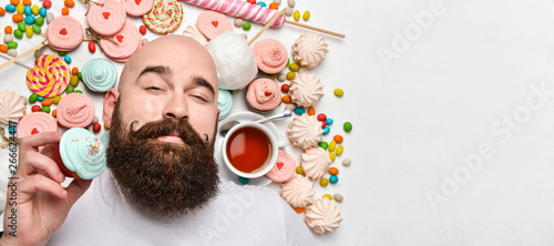 Happy bearded man biting cream cake isolated on white background