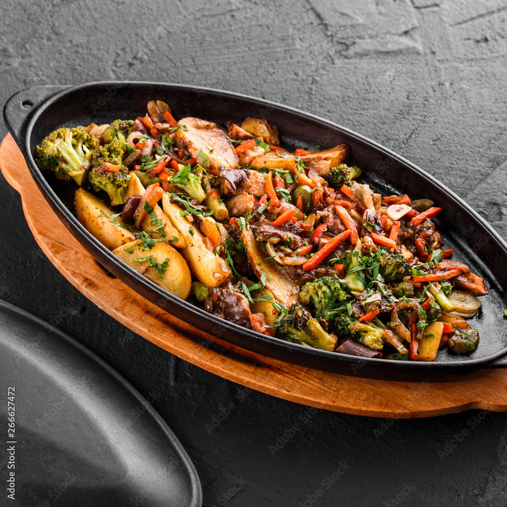 Baked vegetables, greens, potatoes, broccoli in pan on black stone background. Clean eating, healthy vegan food concept. Baked vegetables, greens, potatoes, broccoli in pan on black stone background. Clean eating, healthy vegan food concept.