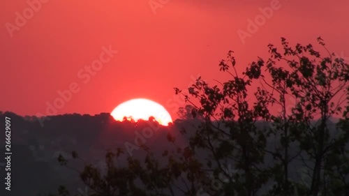 Tropical sunset with clouds. Beautiful sunset image of the golden hour. A dark orange sky with clouds and the shining sun going down.