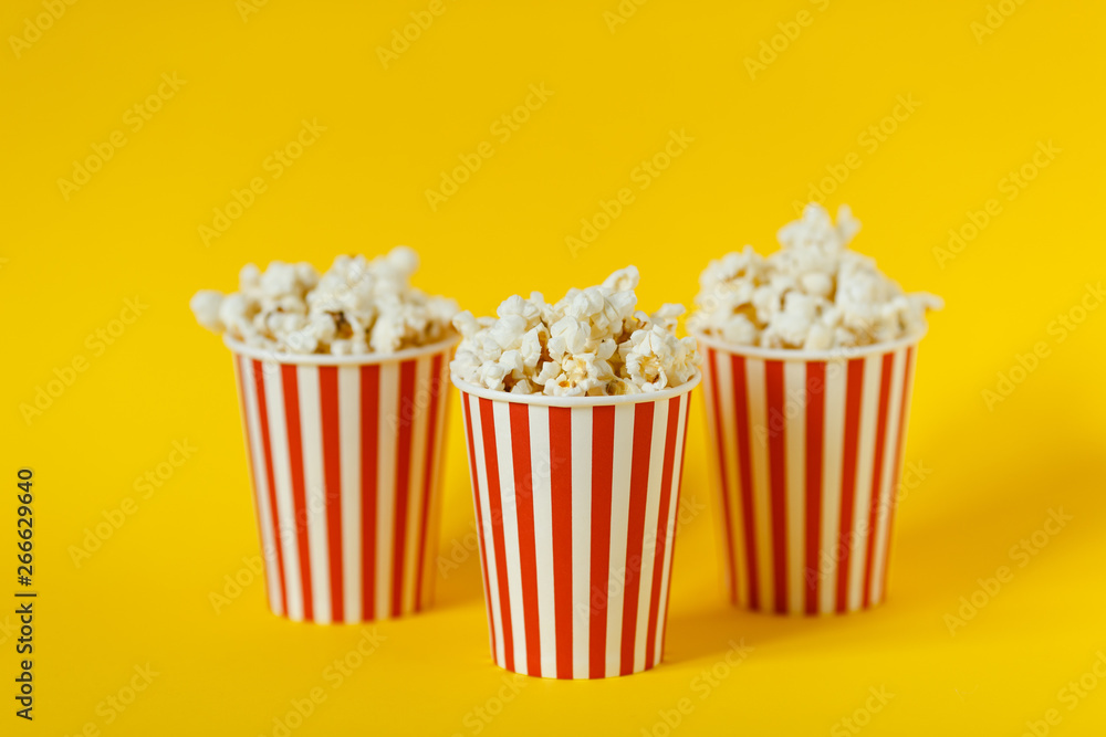 three carton bucket with cinema snack. popcorn and red cups on color yellow background. space for text.