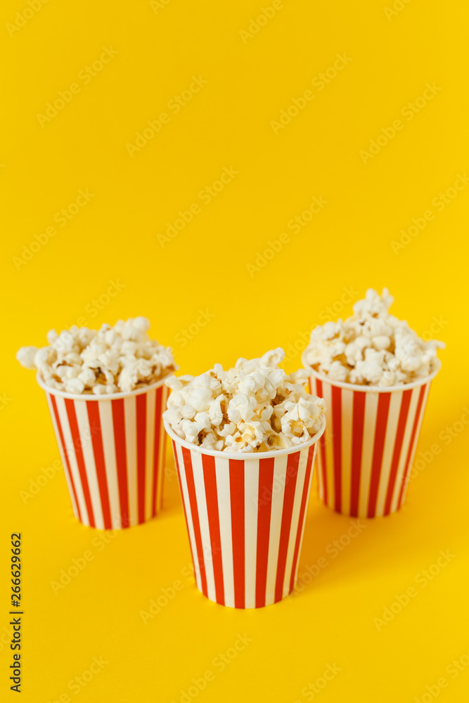 three carton bucket with cinema snack. popcorn and red cups on color yellow background. space for text. side view