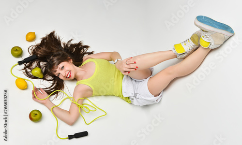 Beauty portrait of a woman surrounded by fruits and a skipping rope lying on the floor. photo