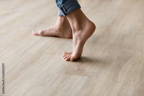 Side closeup view woman feet stands on warm wooden floor photo