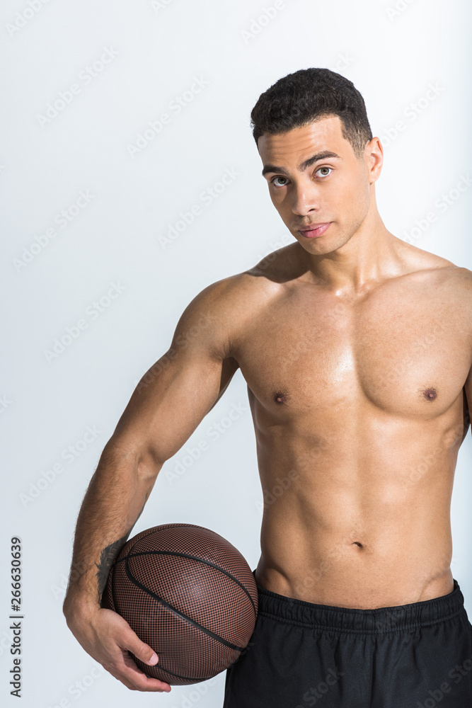 good-looking athletic mixed race man with muscular torso holding brown ball and looking at camera on white good-looking athletic mixed race man with muscular torso holding brown ball and looking at camera on white