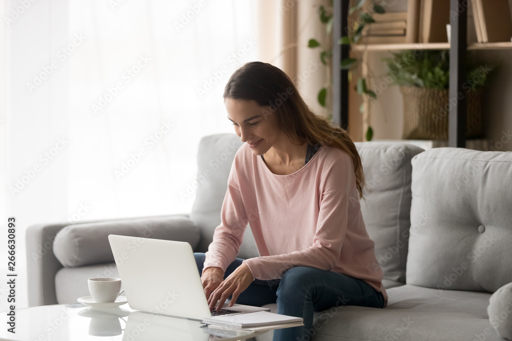 Freelancer woman sitting on couch at home working on computer Freelancer woman sitting on couch at home working on computer