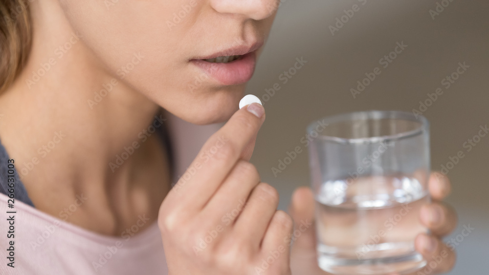 Close up image woman holding pill and glass of water Close up image woman holding pill and glass of water