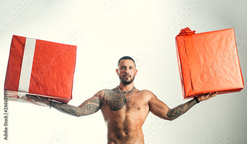 Providing fast gift delivery. Brutal latino man holding gift boxes in strong hands. Bearded hispanic man with wrapped gift boxes. Muscular shirtless guy holiday gifts in red wrap