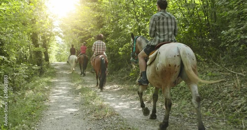 Four active people riding horses on a sunny outdoor wild forest field.Friends italian trip in Umbria.4k slow motion photo