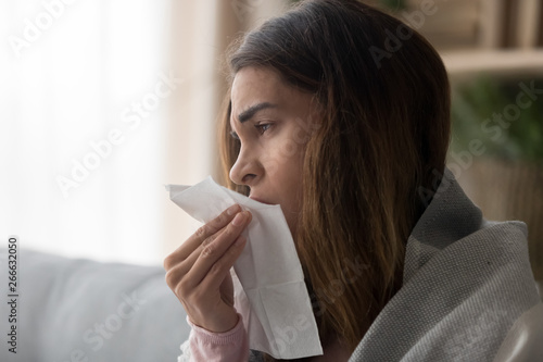 Side view close up woman holding paper tissue sneezing