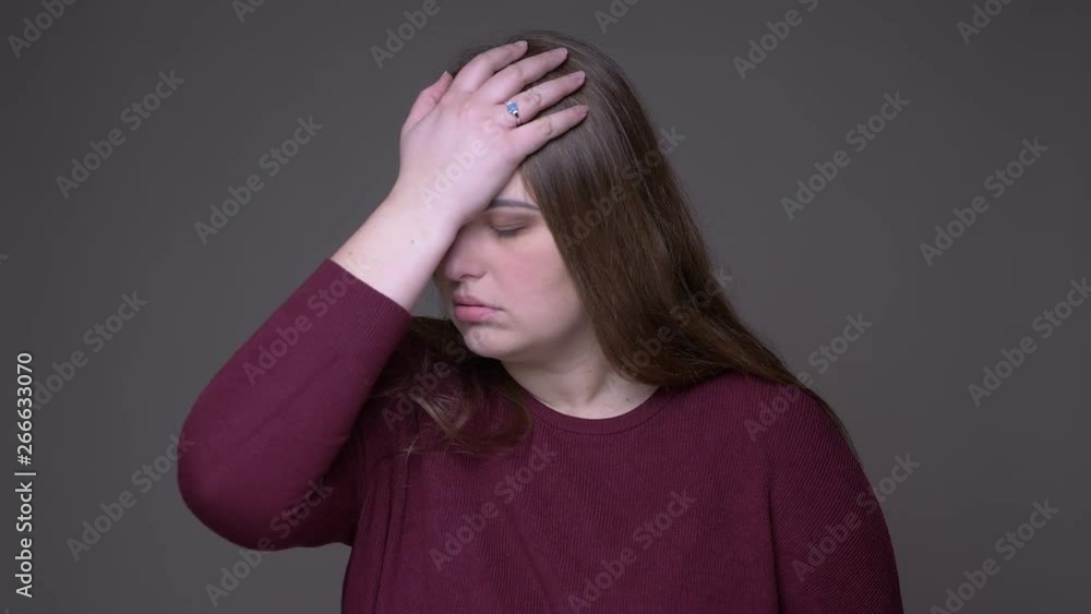 Closeup portarit of young overweight caucasian female being annouyed and irritated looking at camera with background isolated on gray Closeup portarit of young overweight caucasian female being annouyed and irritated looking at camera with background isolated on gray