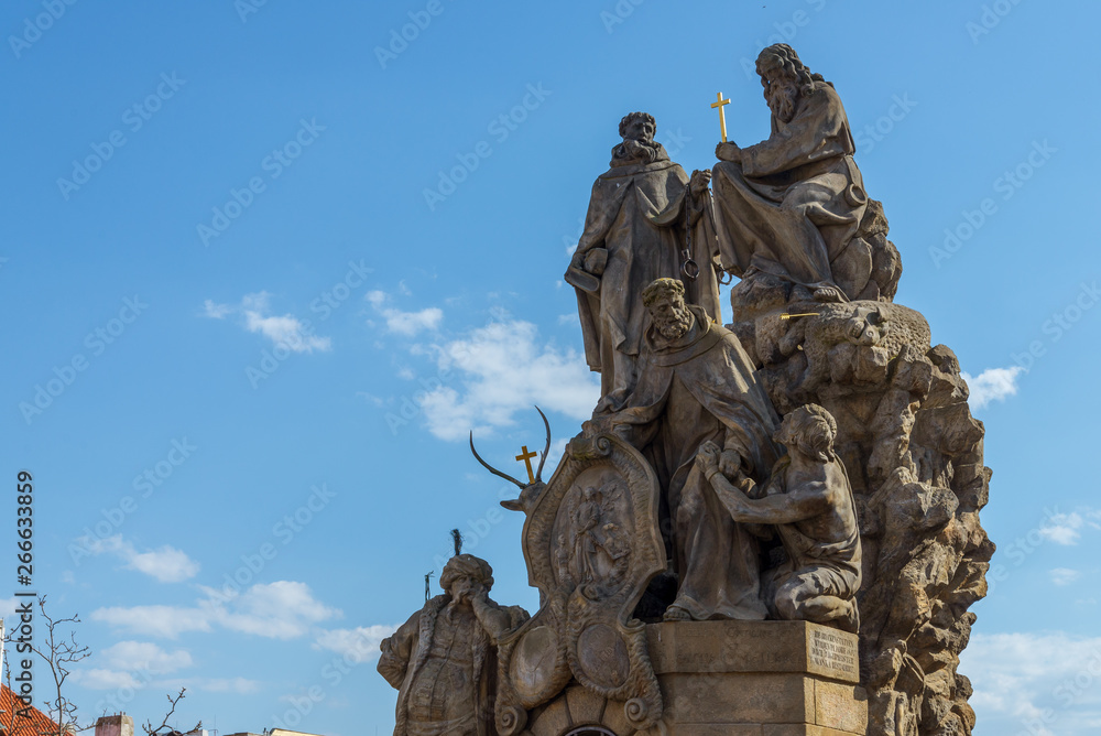 Outdoor sunny view statues of John of Matha, Felix of Valois and Saint Ivan stand on pedestal and balustrade of Charles Bridge.  