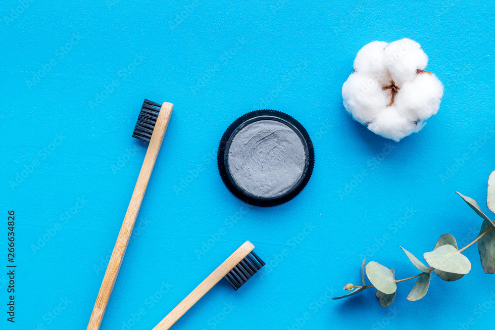 Dental care with eco friendly bamboo tooth brush and carbon toothpaste on blue background top view Dental care with eco friendly bamboo tooth brush and carbon toothpaste on blue background top view