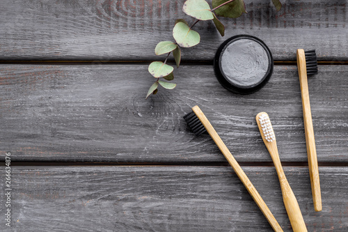 Eco materials concept with bamboo tooth brush and toothpaste with bamboo carbon on wooden background top view copy space