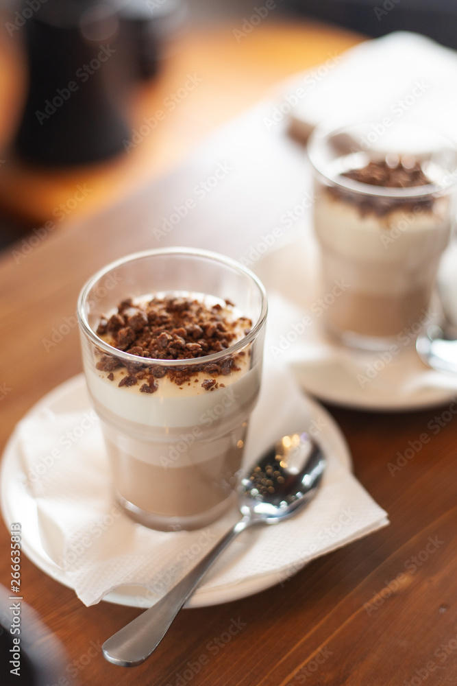 Layered vanilla-chocolate mousse with topping on a wooden rustic table Layered vanilla-chocolate mousse with topping on a wooden rustic table