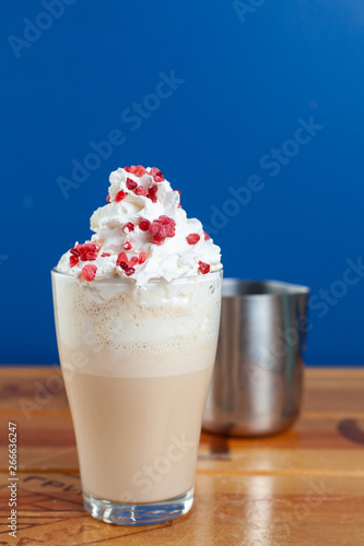Delicate coffee with milk and whipped cream on a bright blue background