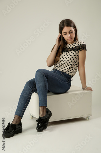 Full-length portrait of a beautiful young woman in the studio wearing polka dots blouse and jeans