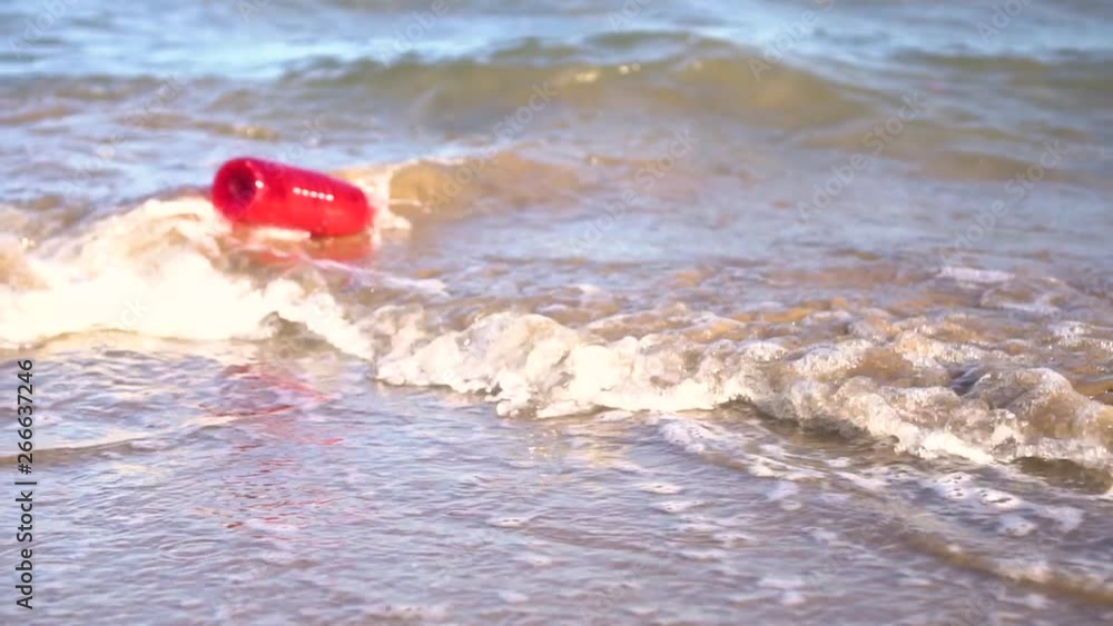 120fps: Red plastic bottle drift in water. Waste getting thrown on the beach by the waves. Sea Ocean pollution concept. 