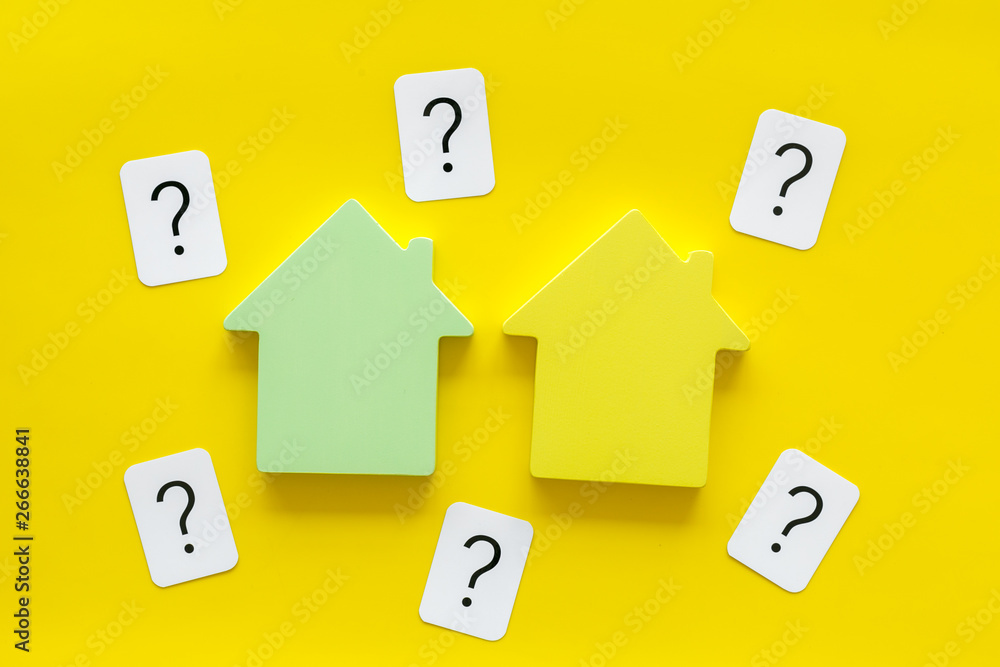 Buy house with house figure and question mark on office desk yellow background top view Buy house with house figure and question mark on office desk yellow background top view