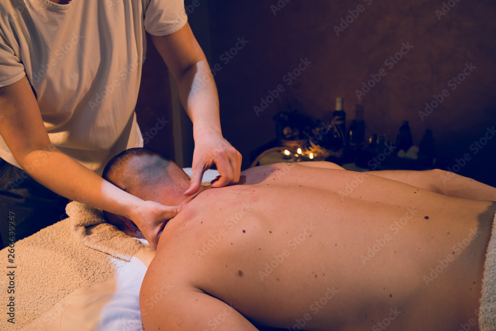 Young woman female massage therapist giving professional massaging relax sport to young athlete at spa studio Young woman female massage therapist giving professional massaging relax sport to young athlete at spa studio